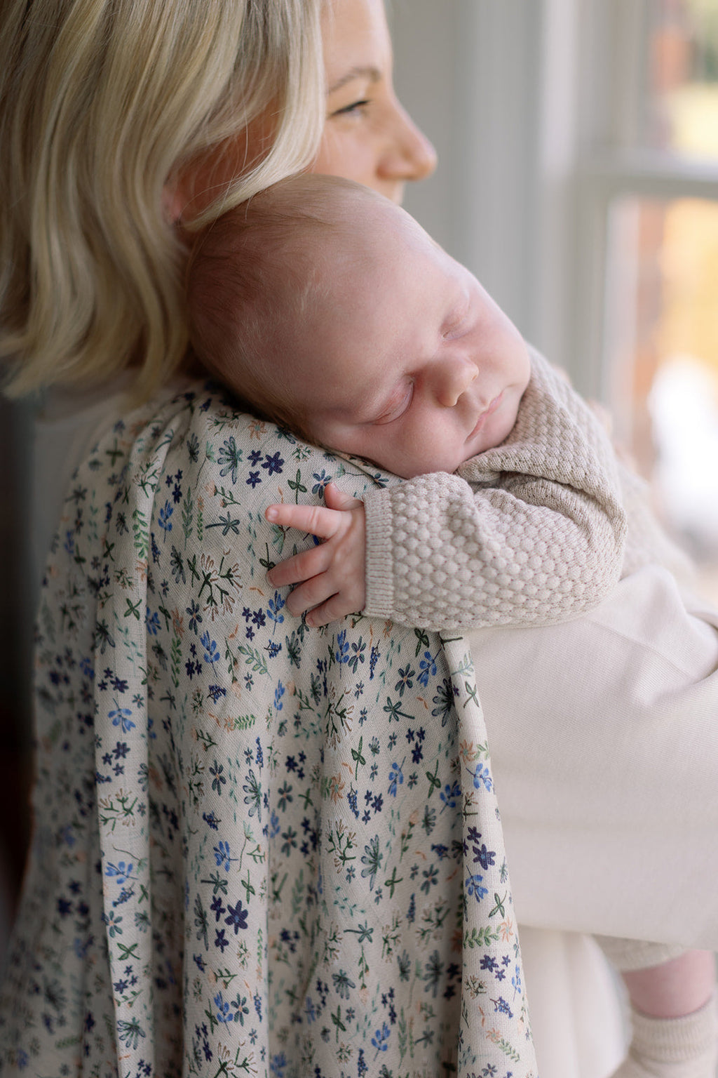 Woman holding a baby wrapped in a floral blanket