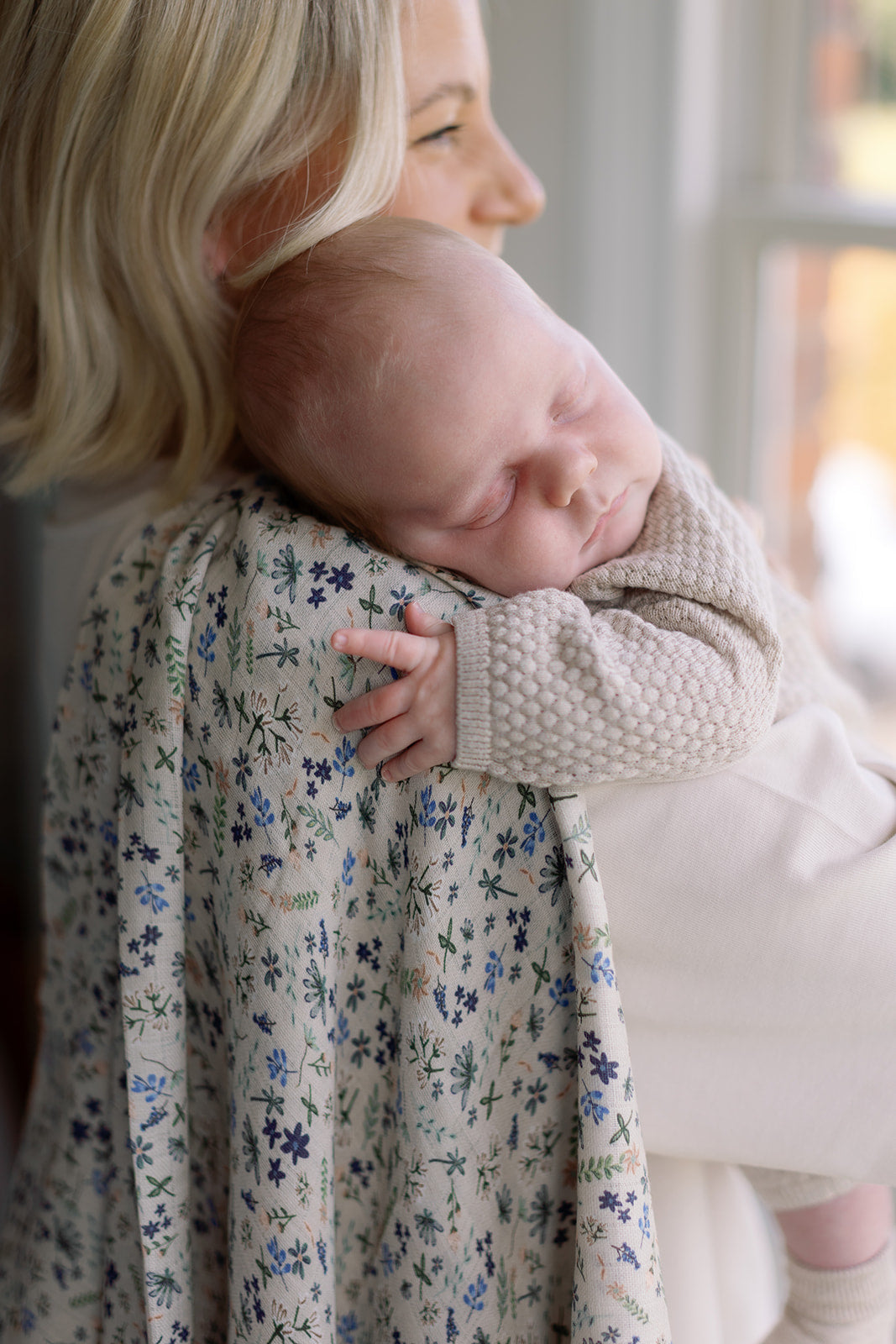 Woman holding a baby wrapped in a floral blanket