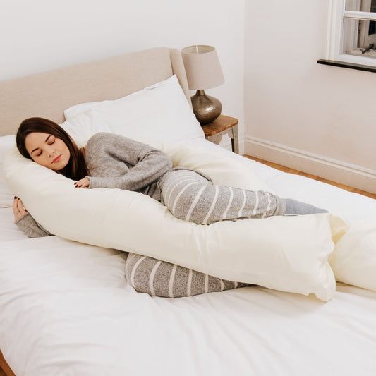 Woman lying on a bed with a large U-shaped body pillow