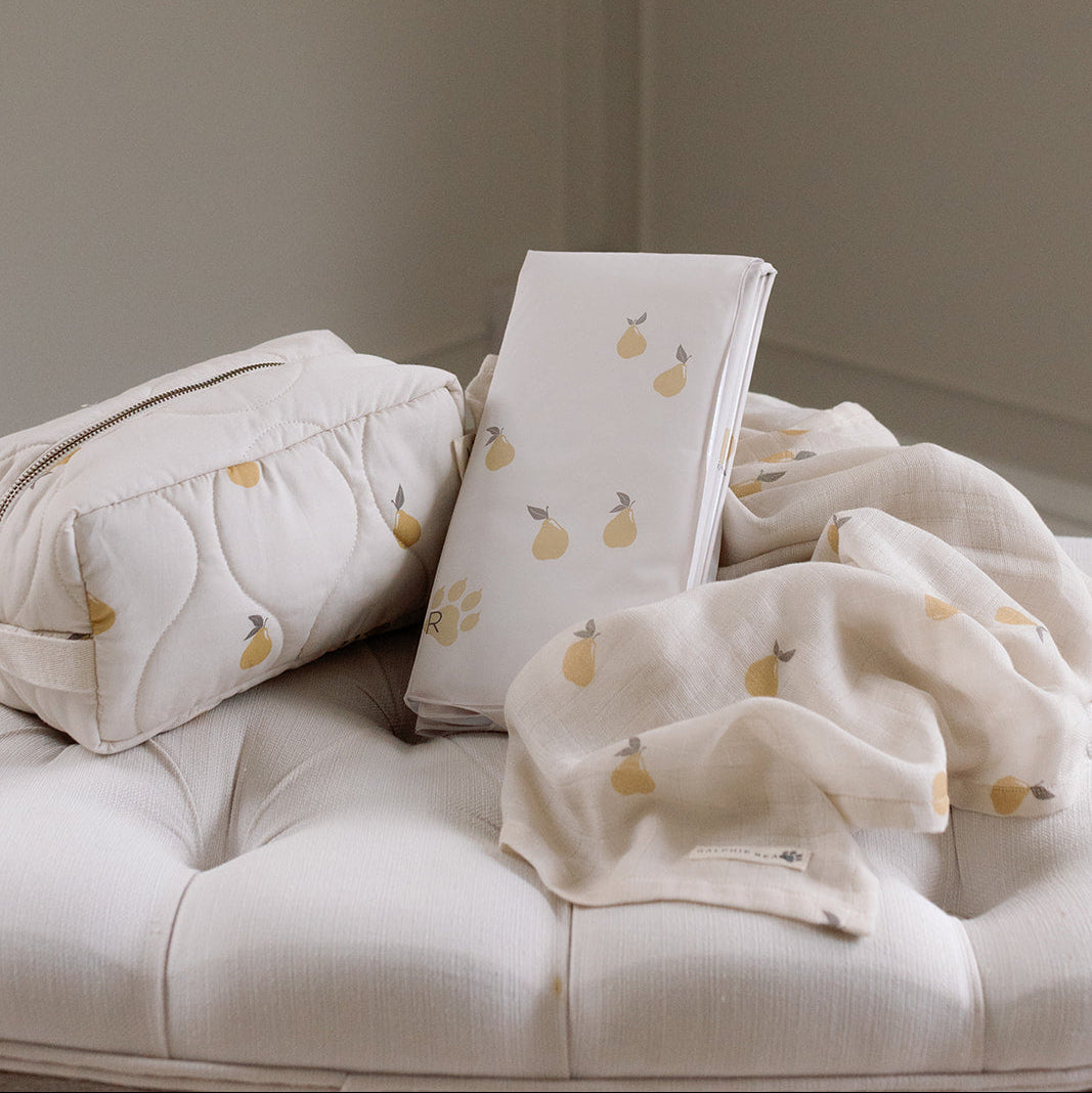 Baby items including a pillow, blanket, and toy on a white surface with a neutral background