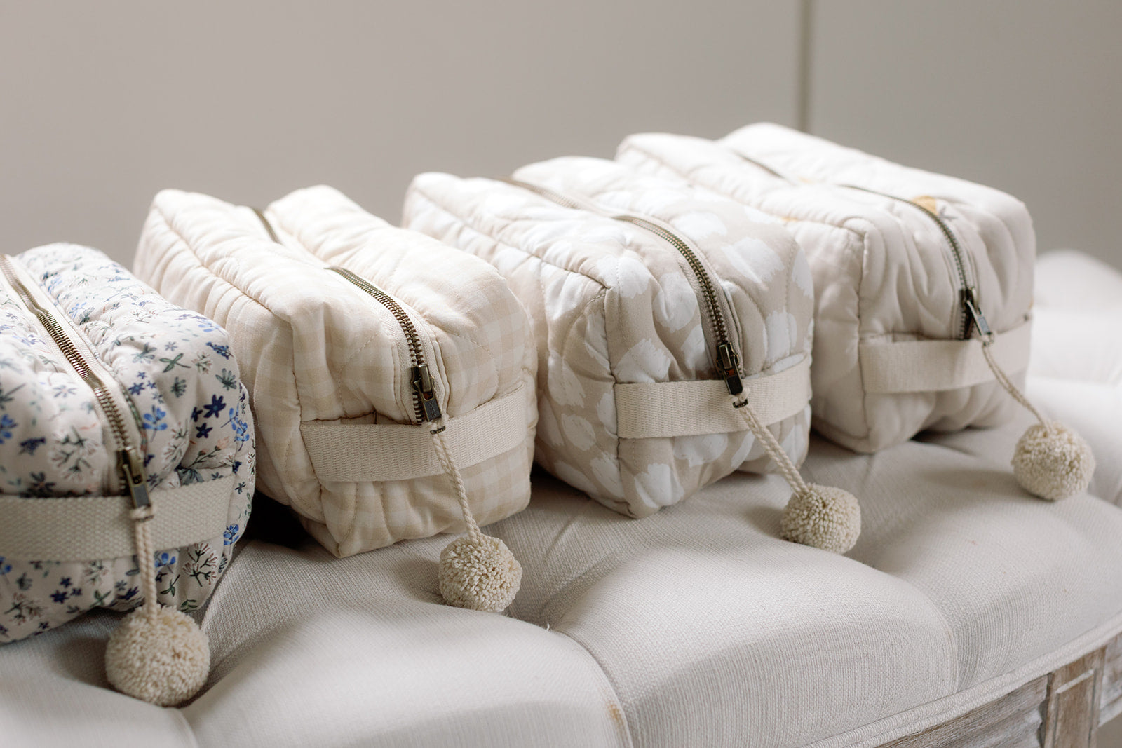 Set of quilted bags with pom-poms on a light-colored surface