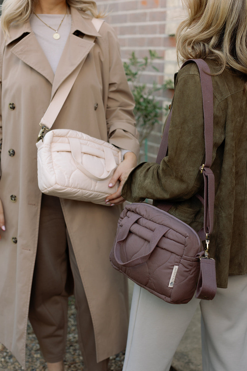 Two women holding textured handbags with a blurred background
