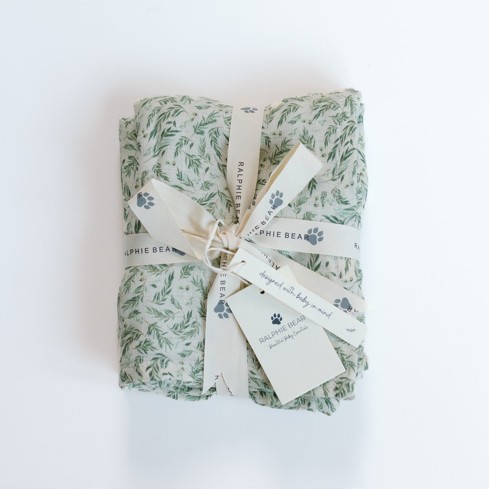 Rolled-up blanket with green leaf pattern and 'Sophie Bear' branding on a white background