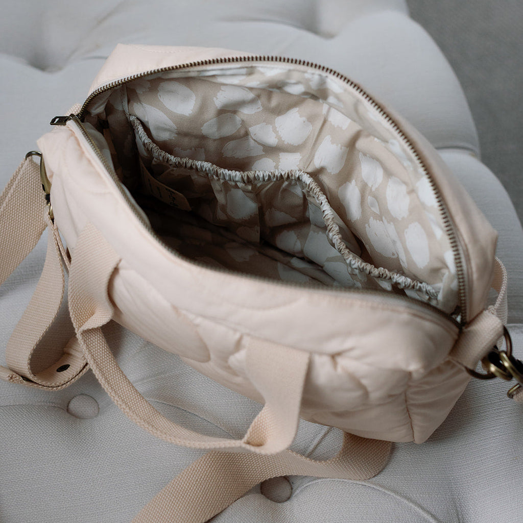 Beige handbag with marble interior on a light gray cushion