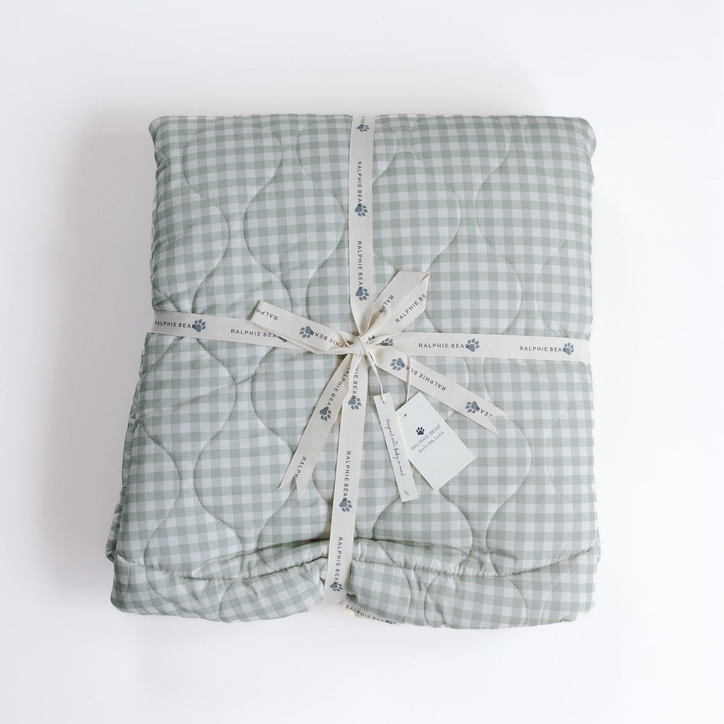 Folded green checkered blanket with a ribbon on a white background