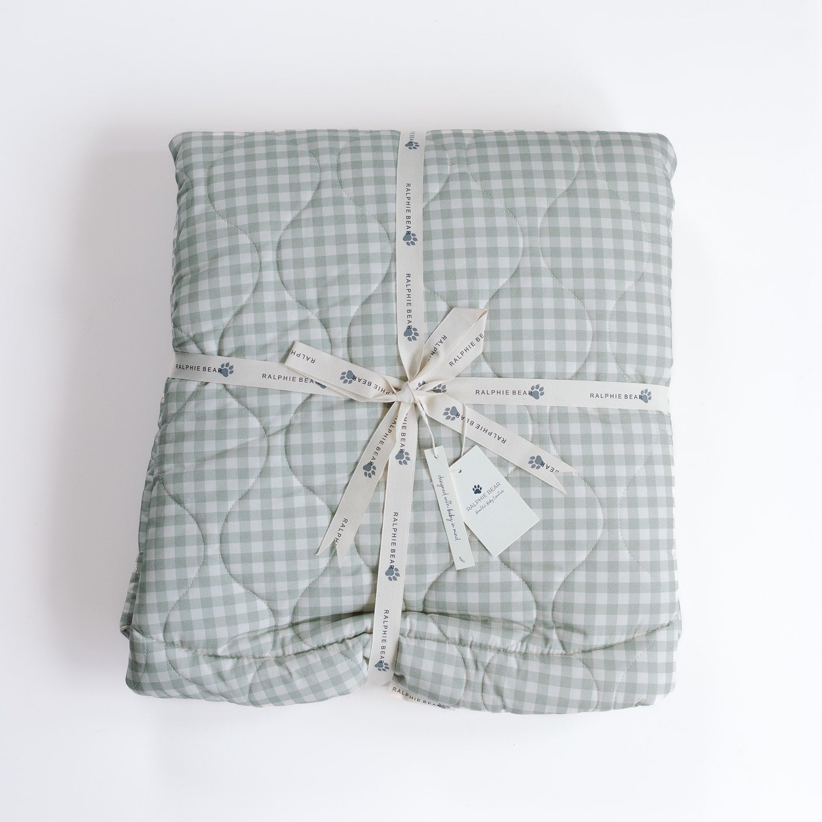 Folded green checkered blanket with a ribbon on a white background