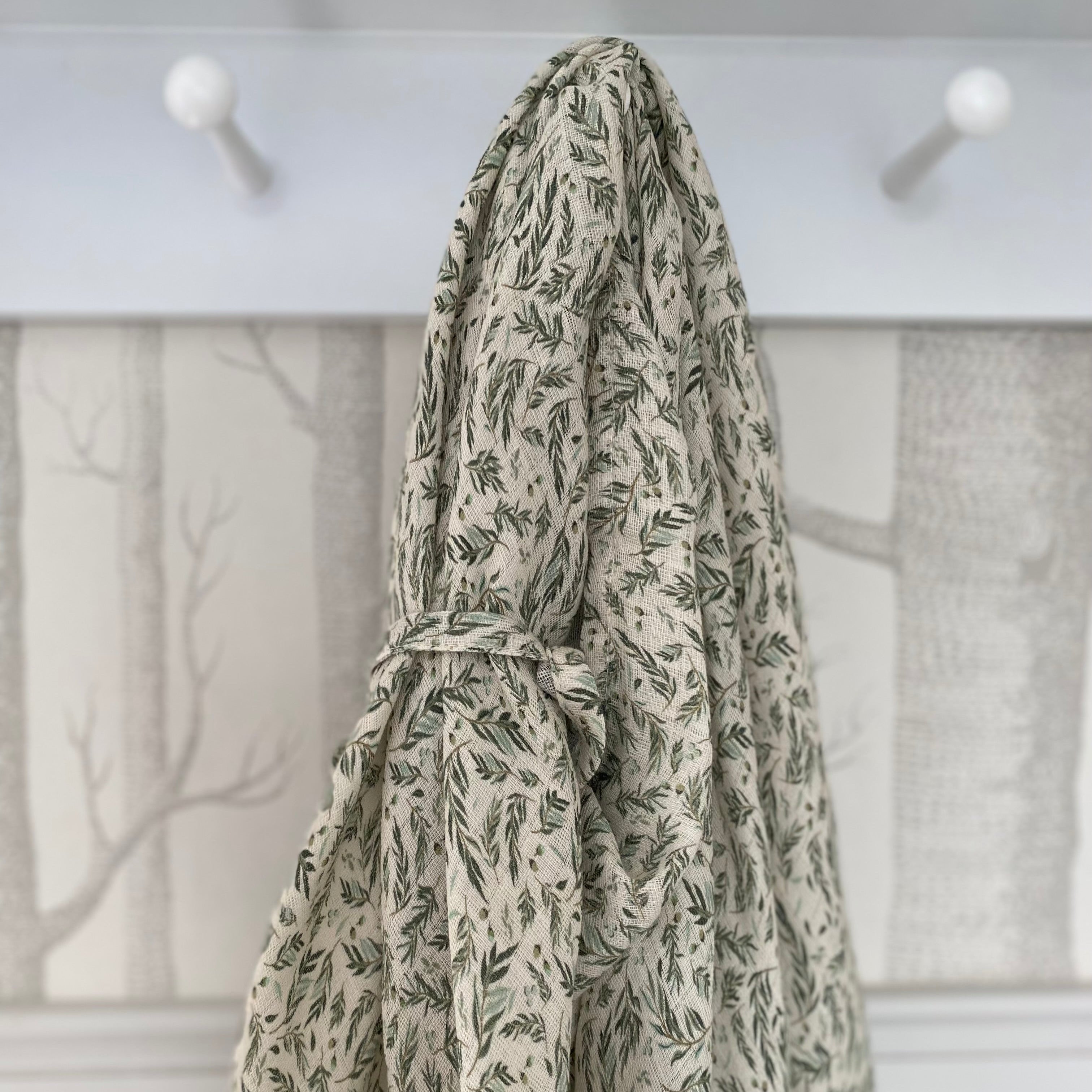 Floral-patterned robe hanging on a hook against a neutral background