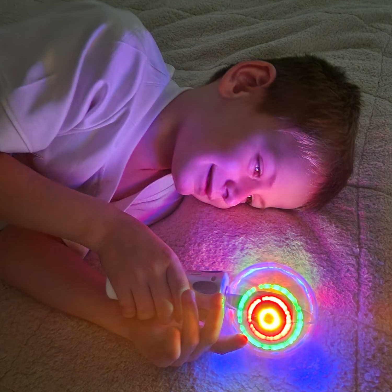 Child playing with a glowing toy on a bed