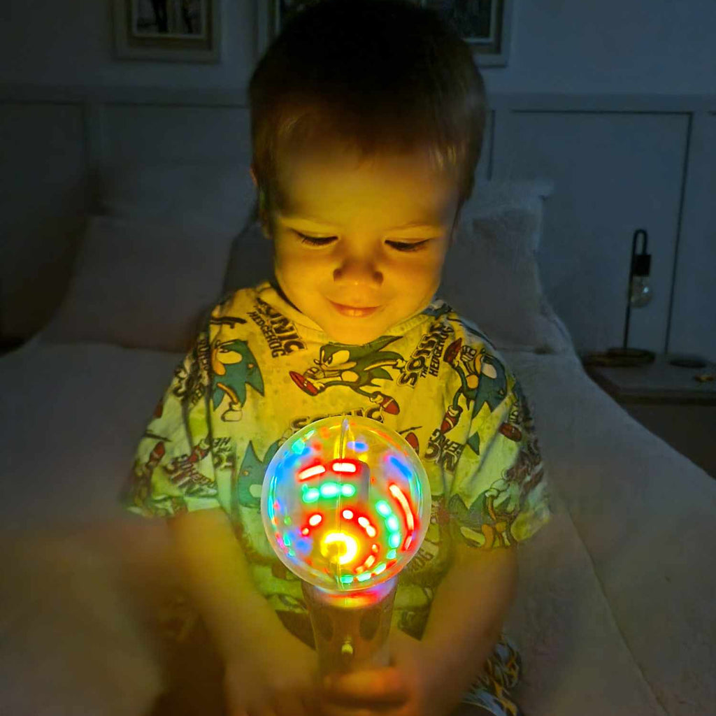 Child holding a colorful发光toy in a dimly lit room