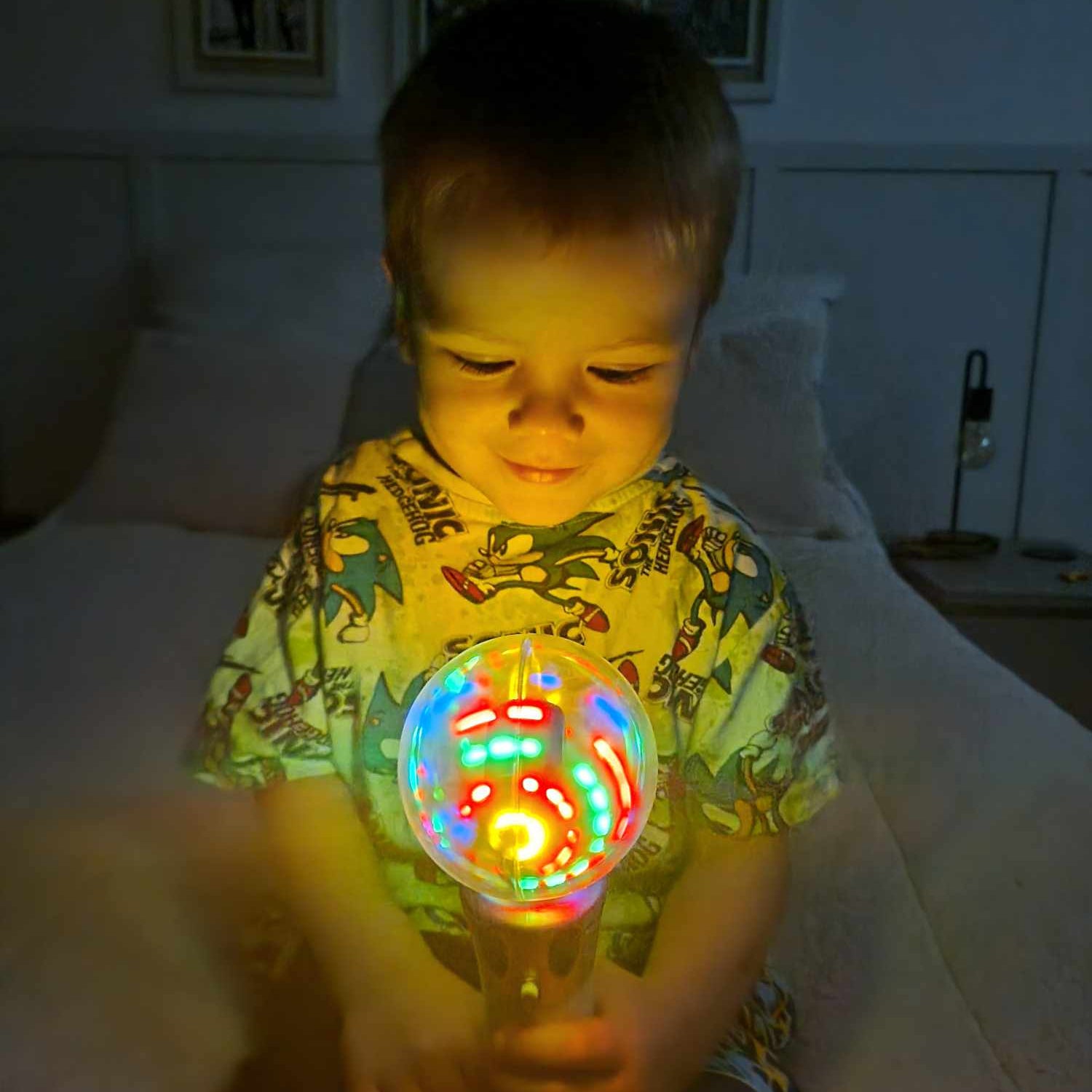 Child holding a colorful发光toy in a dimly lit room