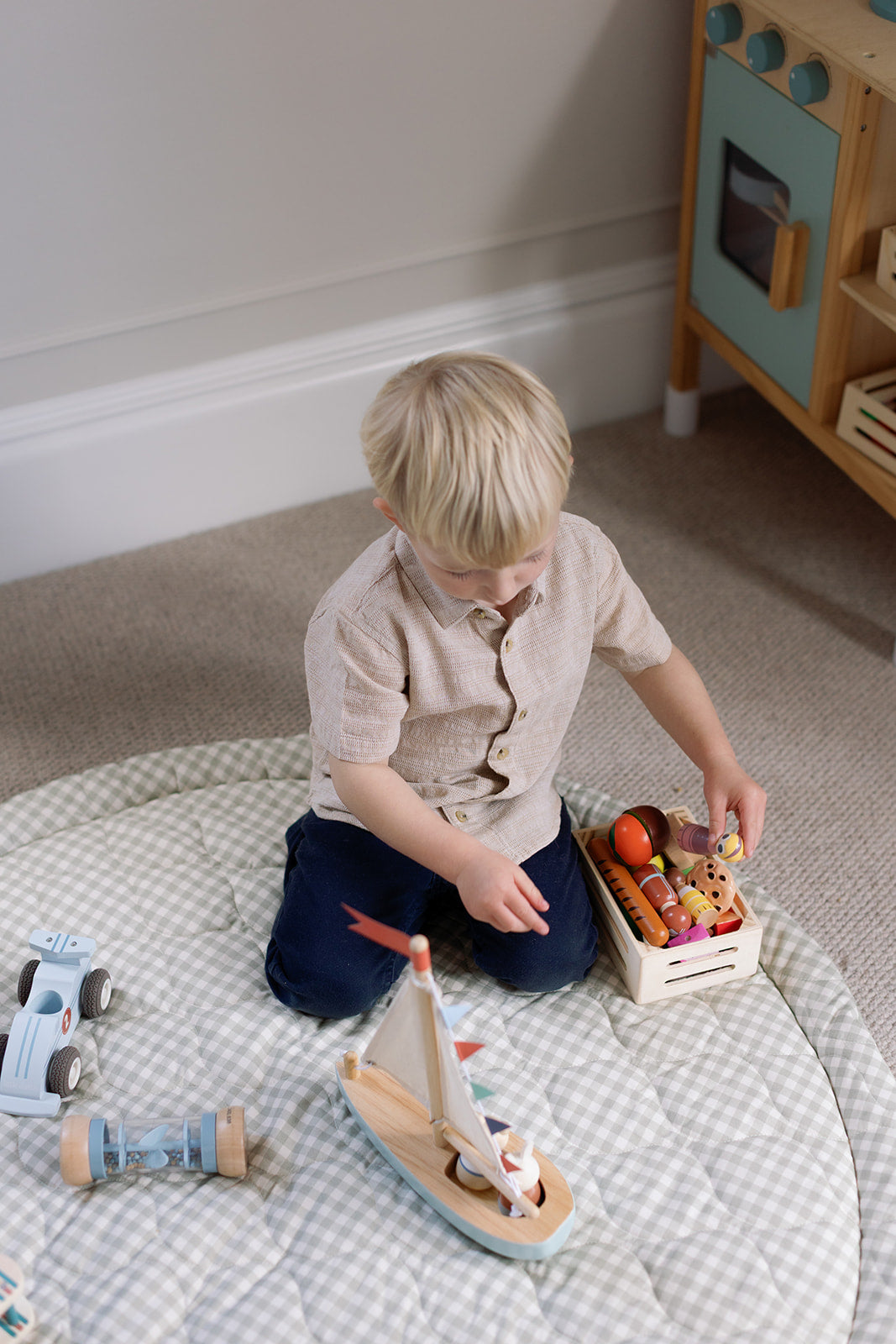 Child playing with wooden toys on a checkered rug