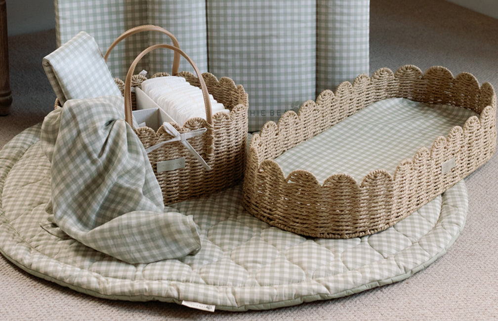 Wicker baby crib with accessories on a checkered blanket