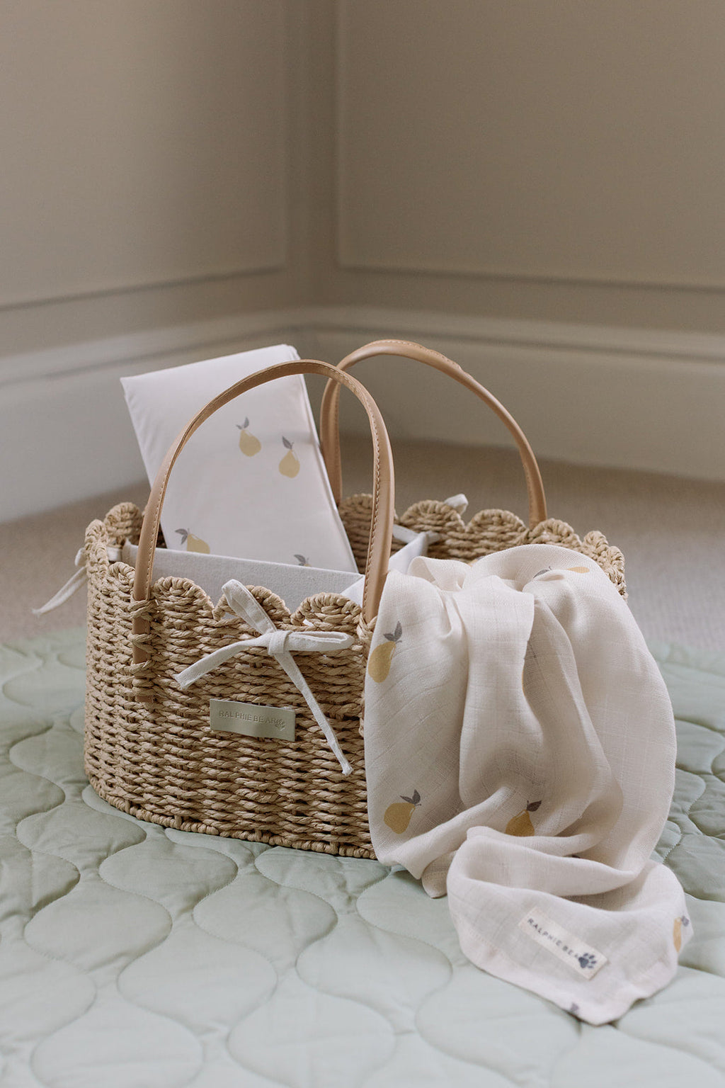 Wicker basket with baby items on a light green surface