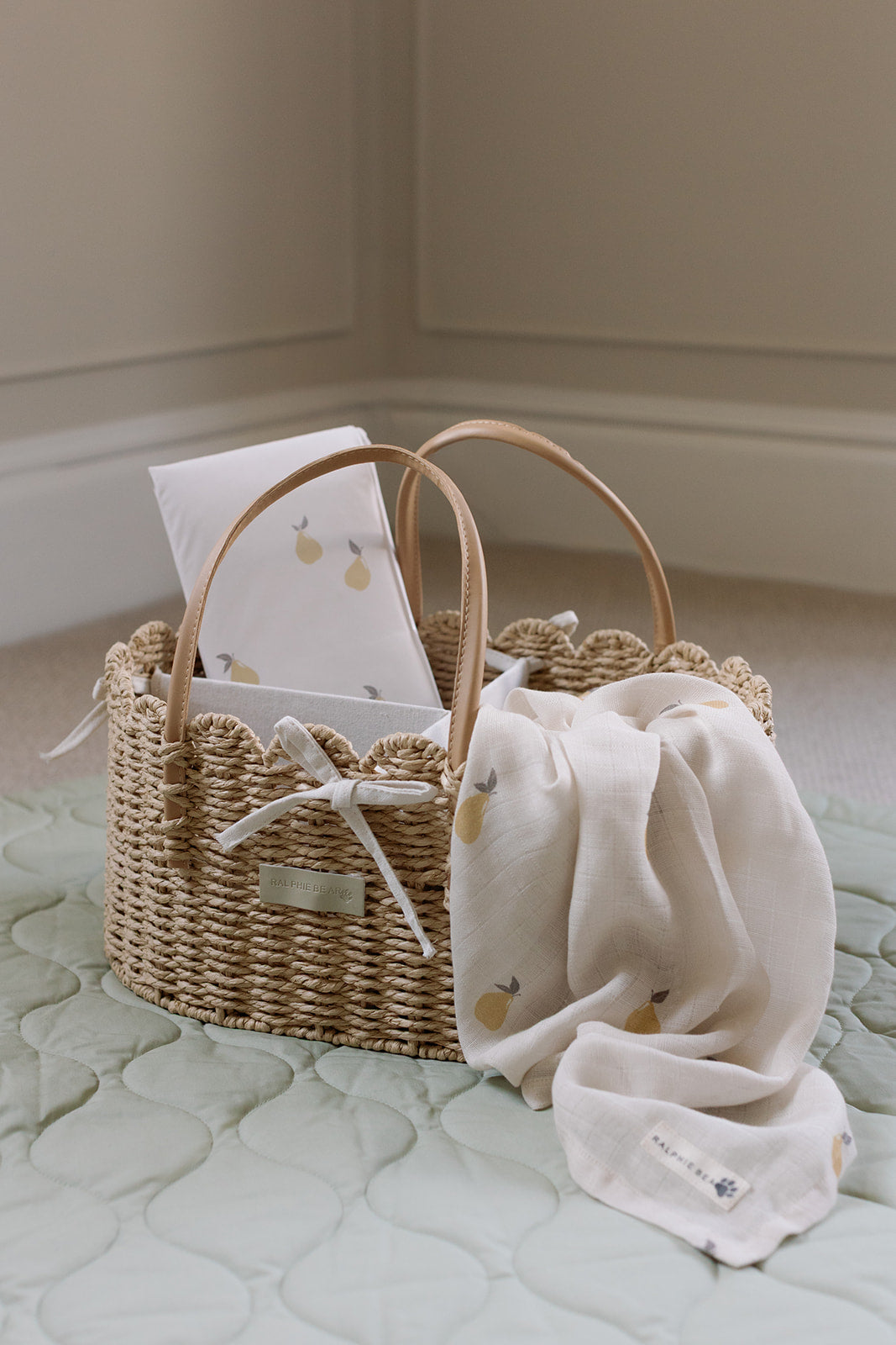 Wicker basket with baby items on a light green surface