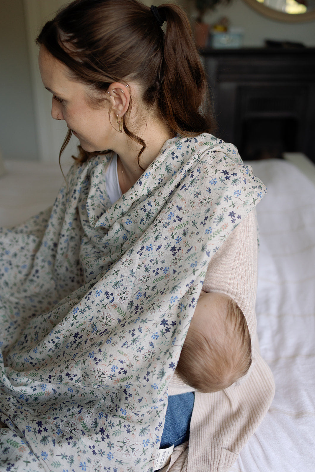 Woman holding a baby wrapped in a floral wrap in a home setting