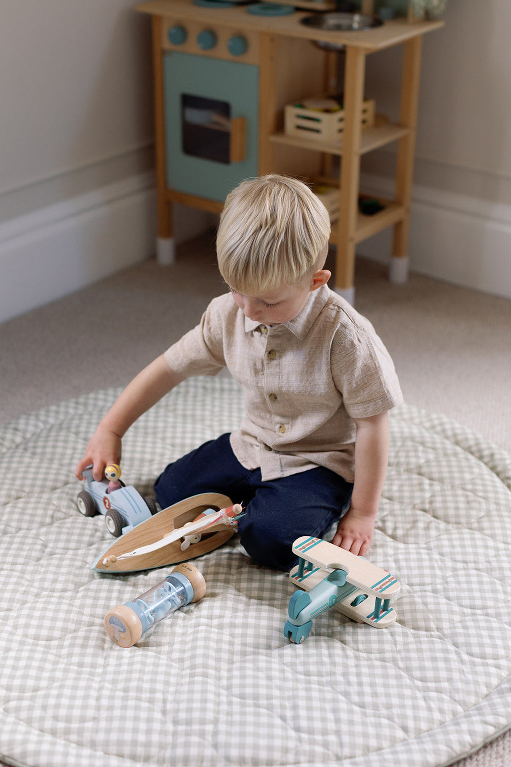 Child playing with wooden toys on a checkered rug