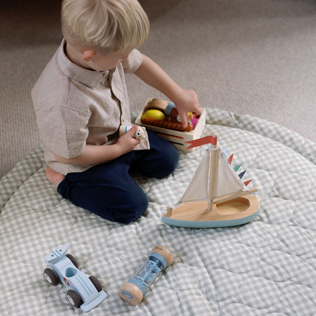 Child playing with wooden toys on a checkered blanket