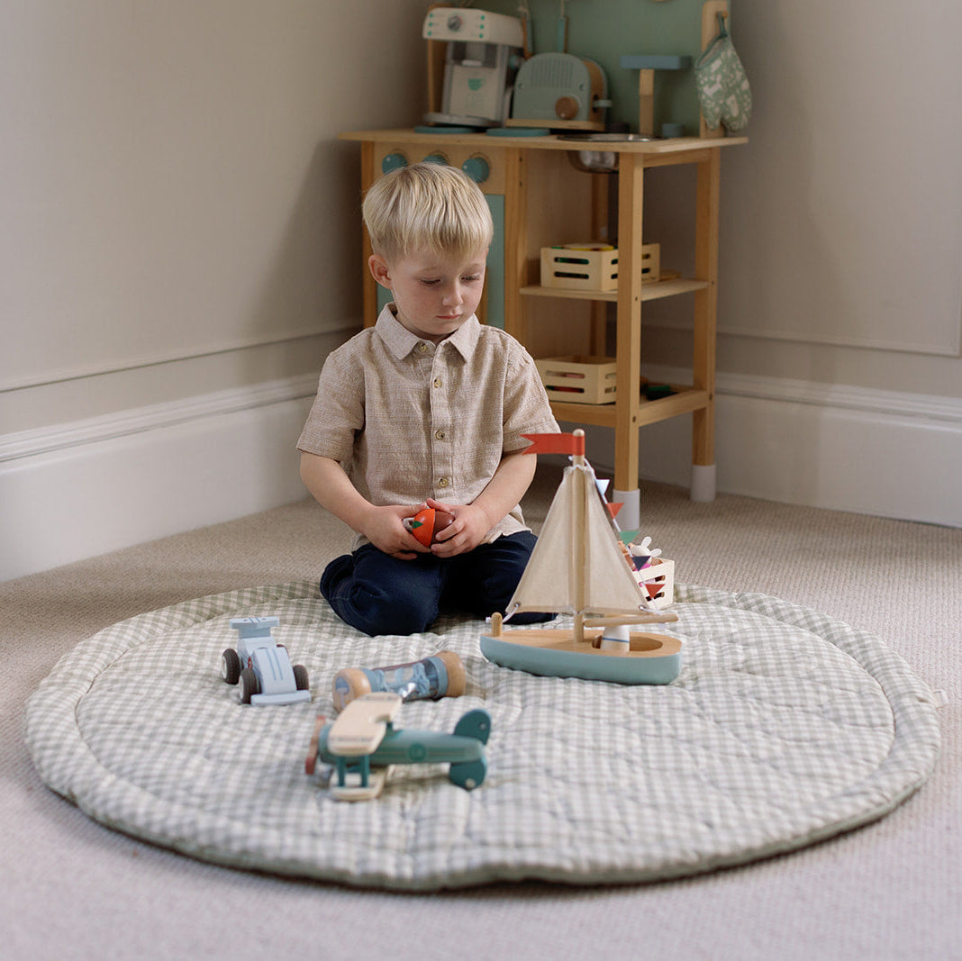Child playing with toys on a round mat in a room with wooden furniture.