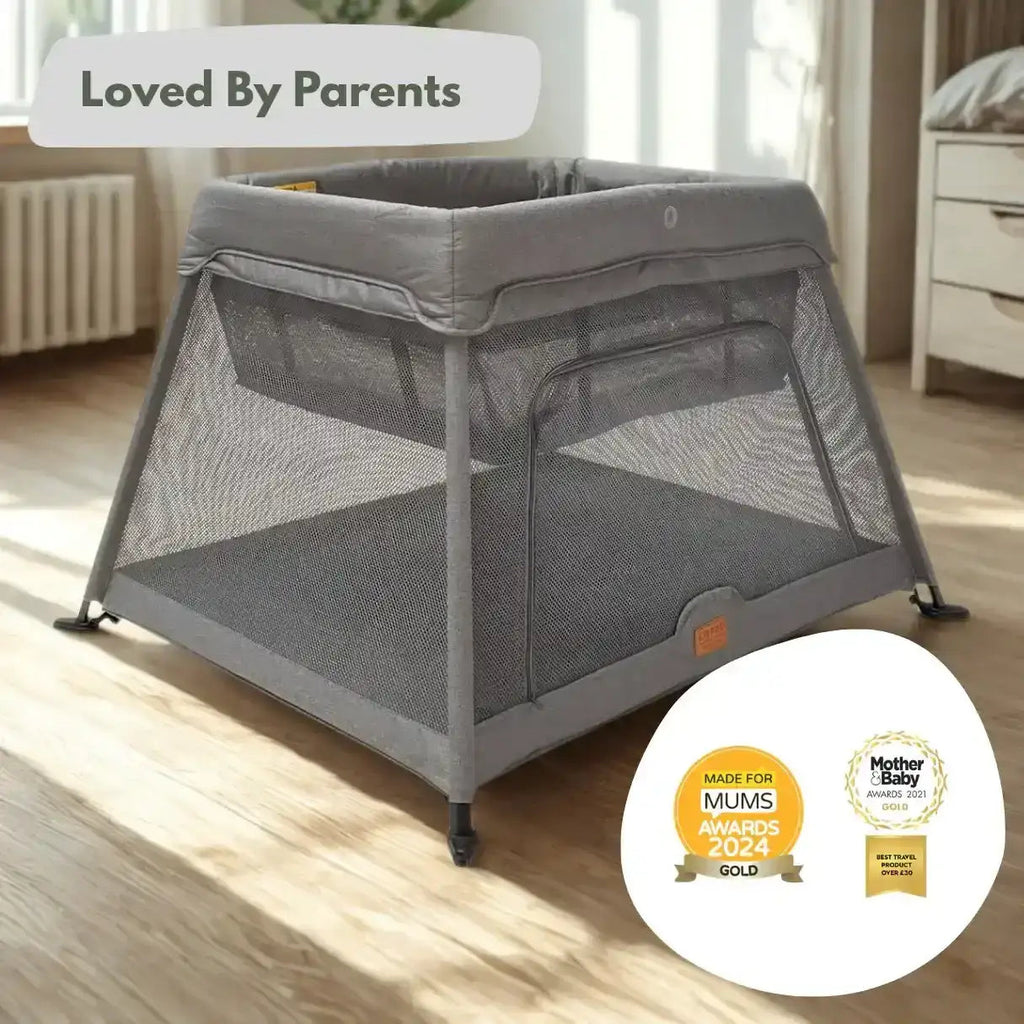Gray baby crib on a wooden floor with 'Loved By Parents' and awards badges displayed.