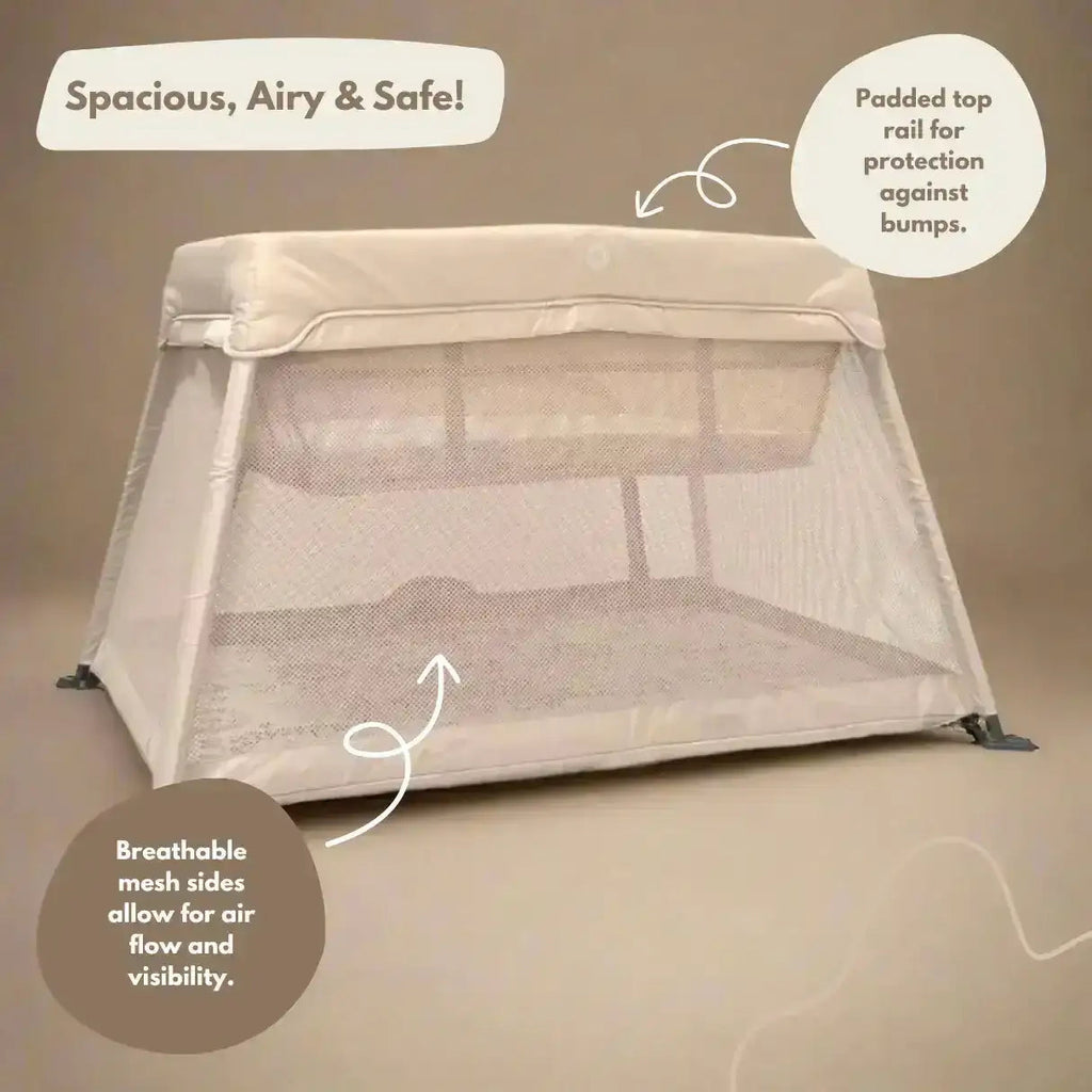 Portable baby crib with mesh sides and top rail on a beige background