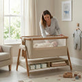 Woman interacting with a baby in a modern crib in a well-lit nursery.