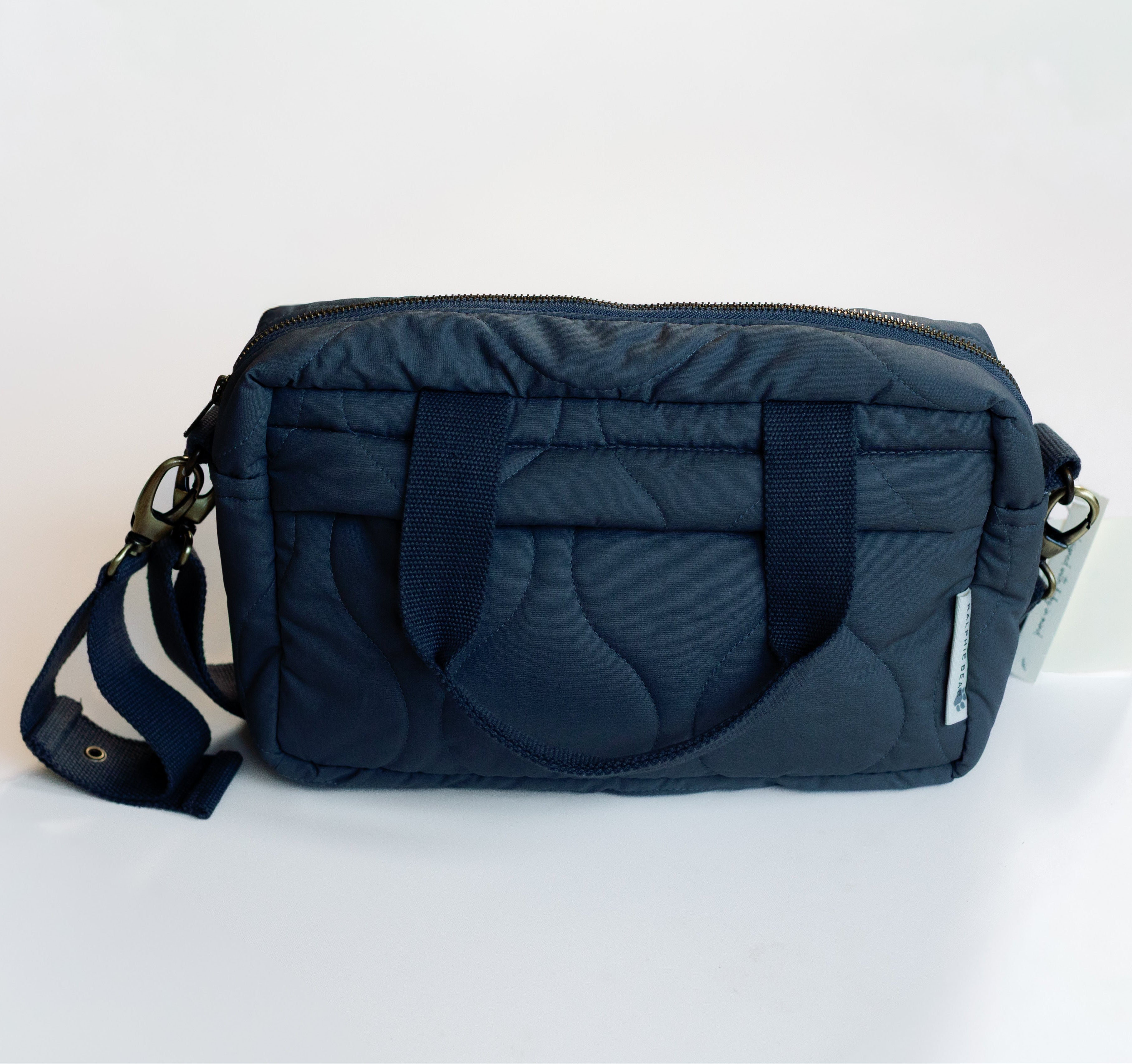 Navy blue quilted handbag with a strap on a white background