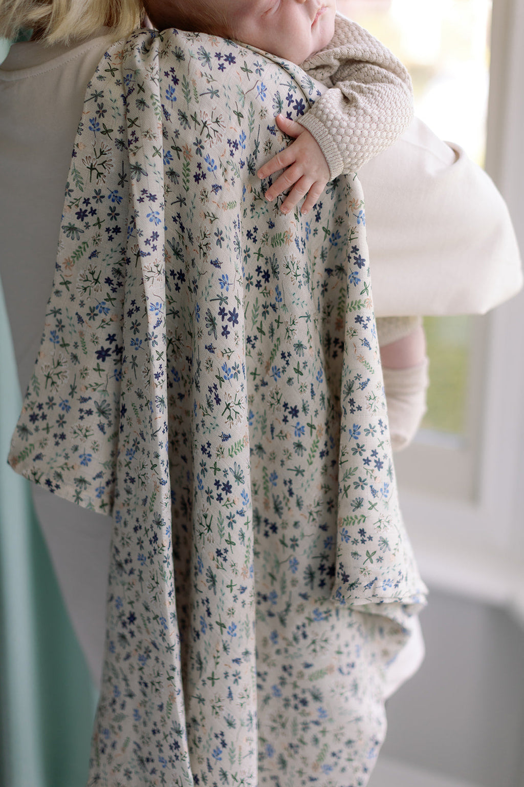 Person holding a floral-patterned blanket with a blurred background
