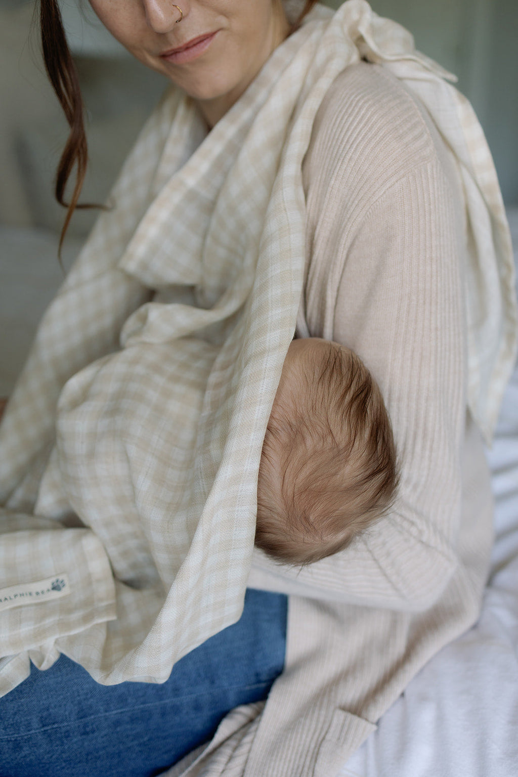Woman holding a baby wrapped in a beige blanket