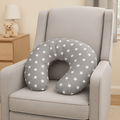 Gray U-shaped pillow with white star pattern on a gray armchair in a room setting.