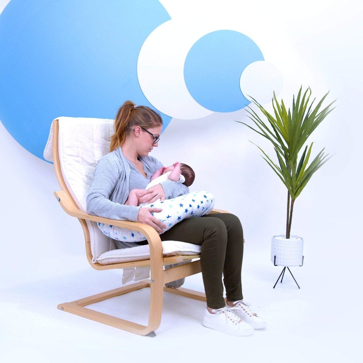 Woman breastfeeding a baby in a rocking chair with a blue and white abstract background