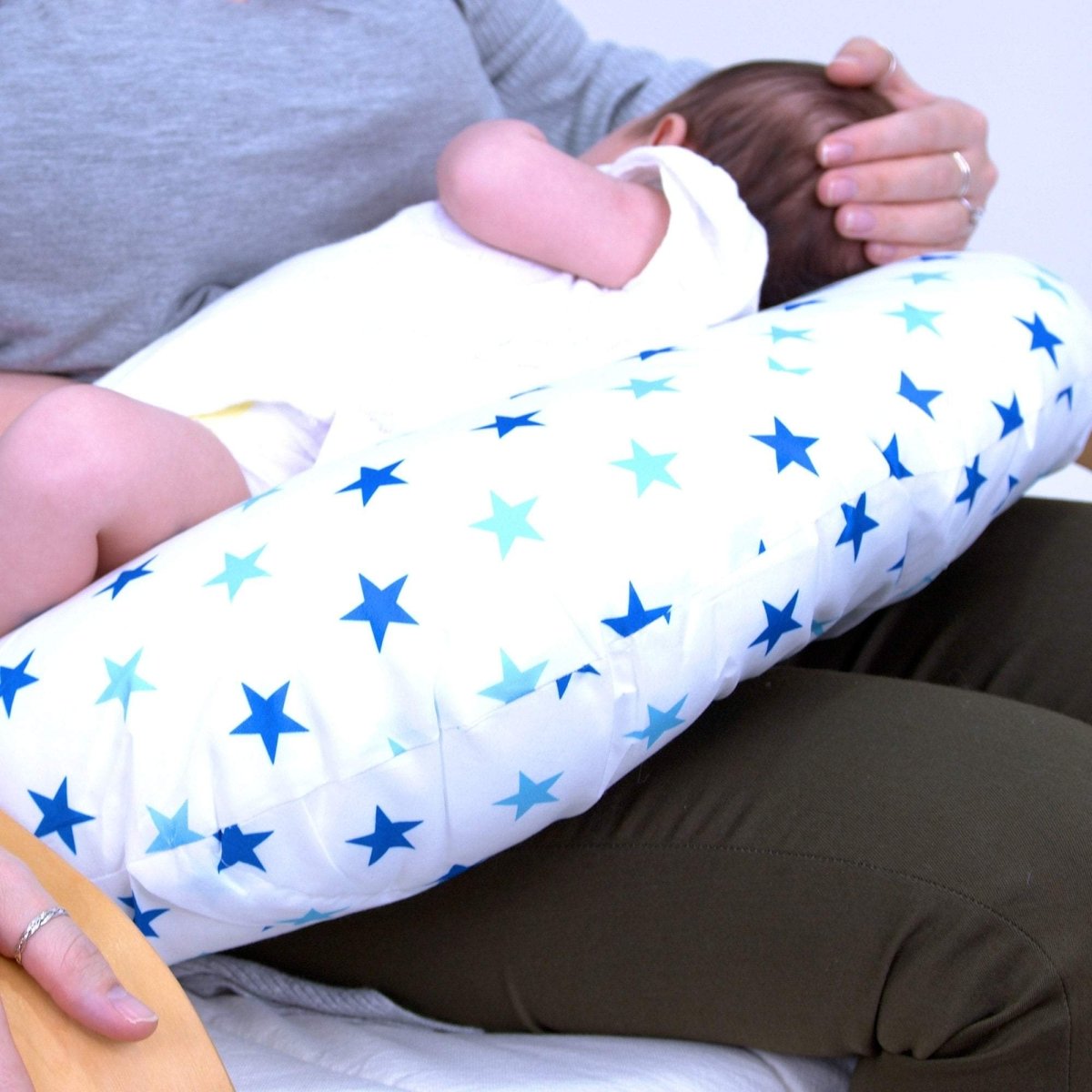 Person holding a baby wrapped in a white blanket with blue star patterns.
