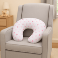 Neck pillow with pink star pattern on a gray armchair in a room setting.