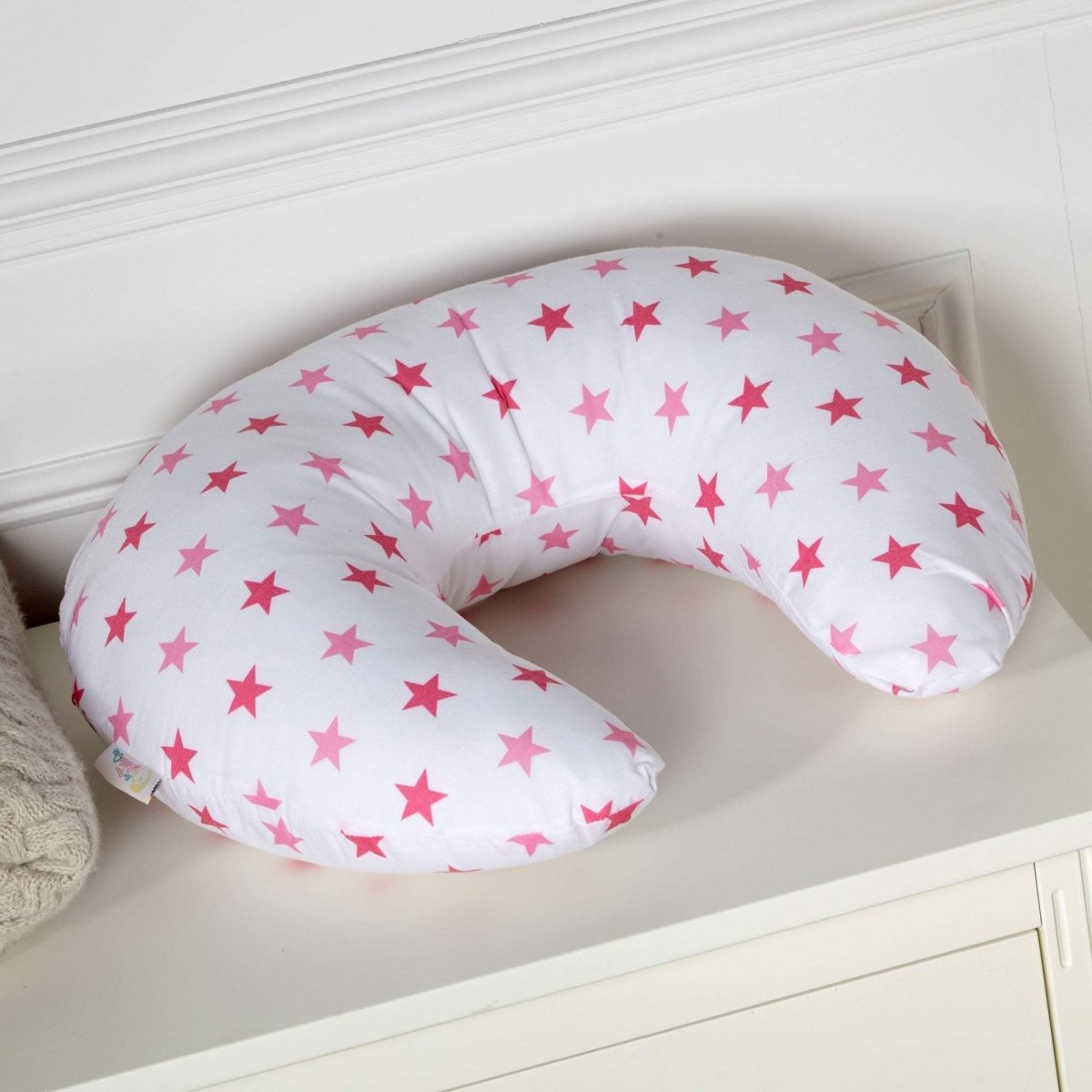 U-shaped pillow with pink star pattern on a white surface