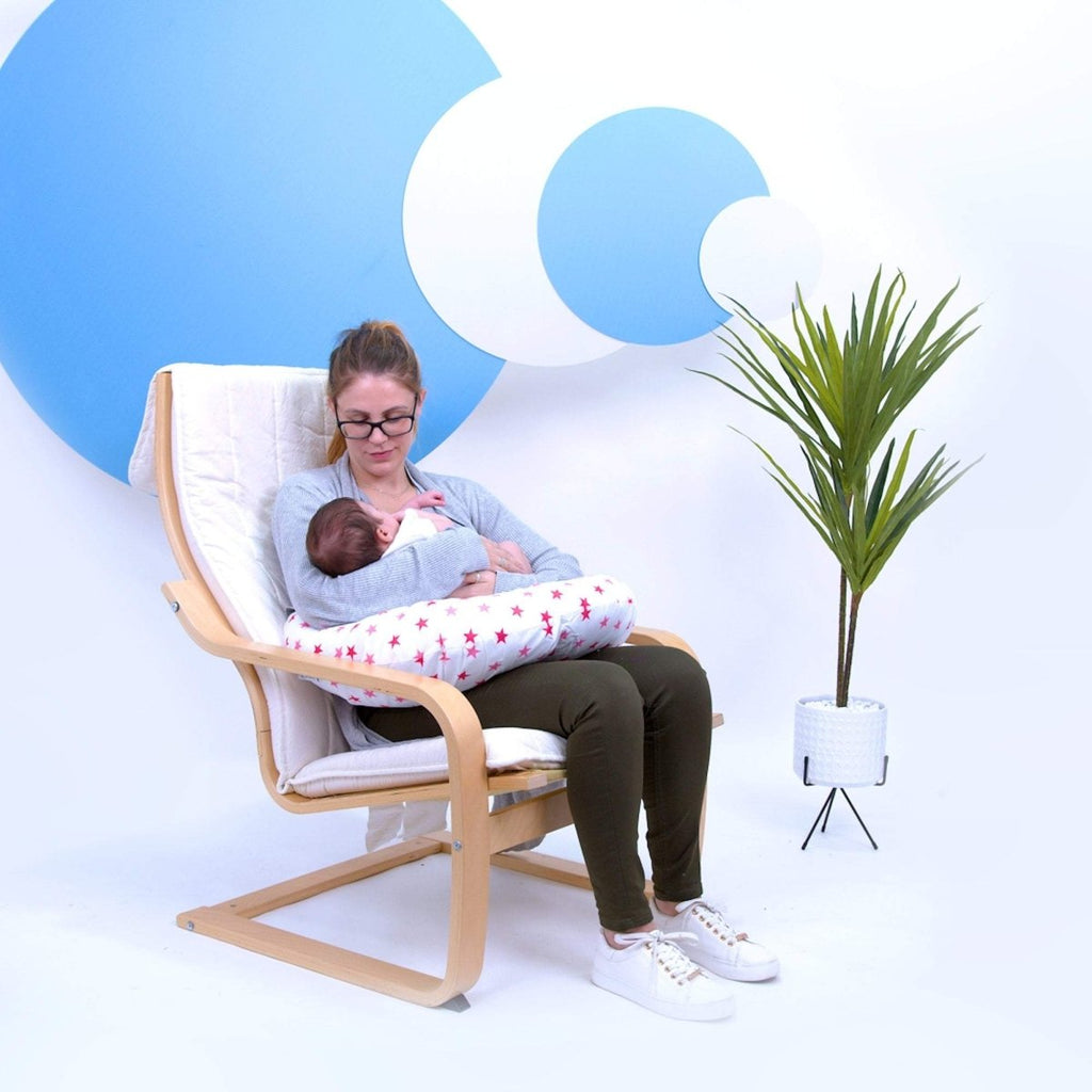 Woman breastfeeding a baby in a modern chair with a minimalistic background