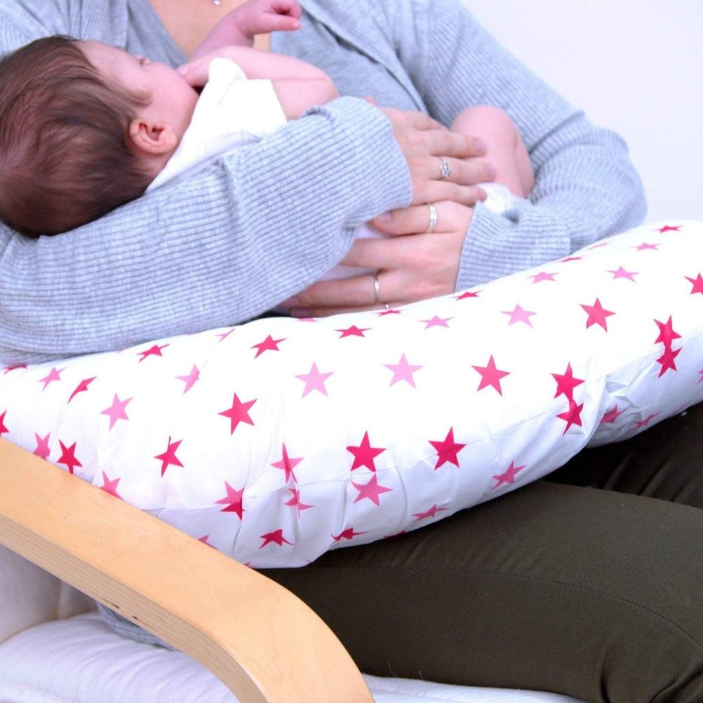 Person holding a baby with a star-patterned cushion on a couch