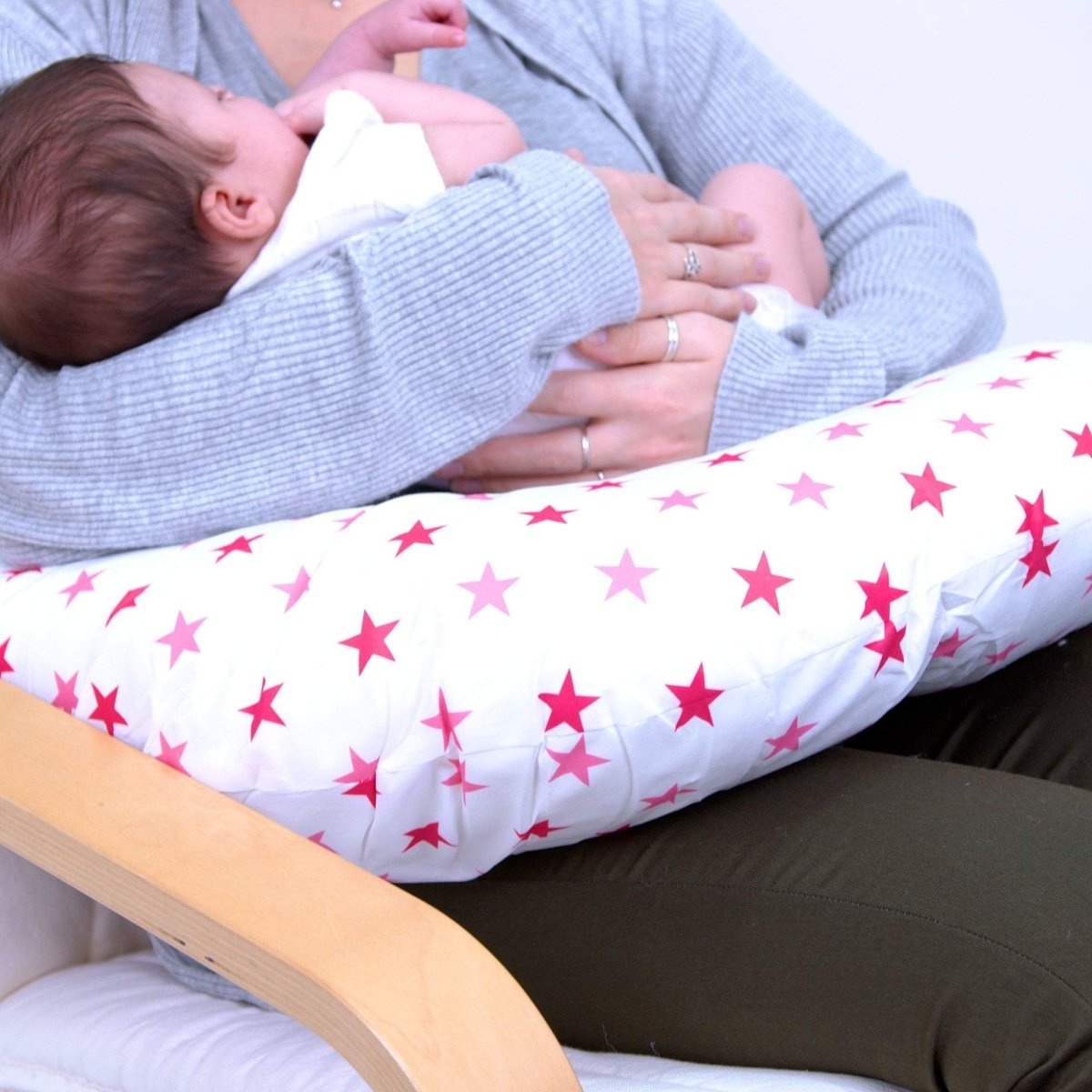 Person holding a baby with a star-patterned cushion on a couch