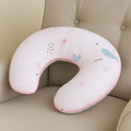 Pink neck pillow with star and balloon patterns on a beige couch