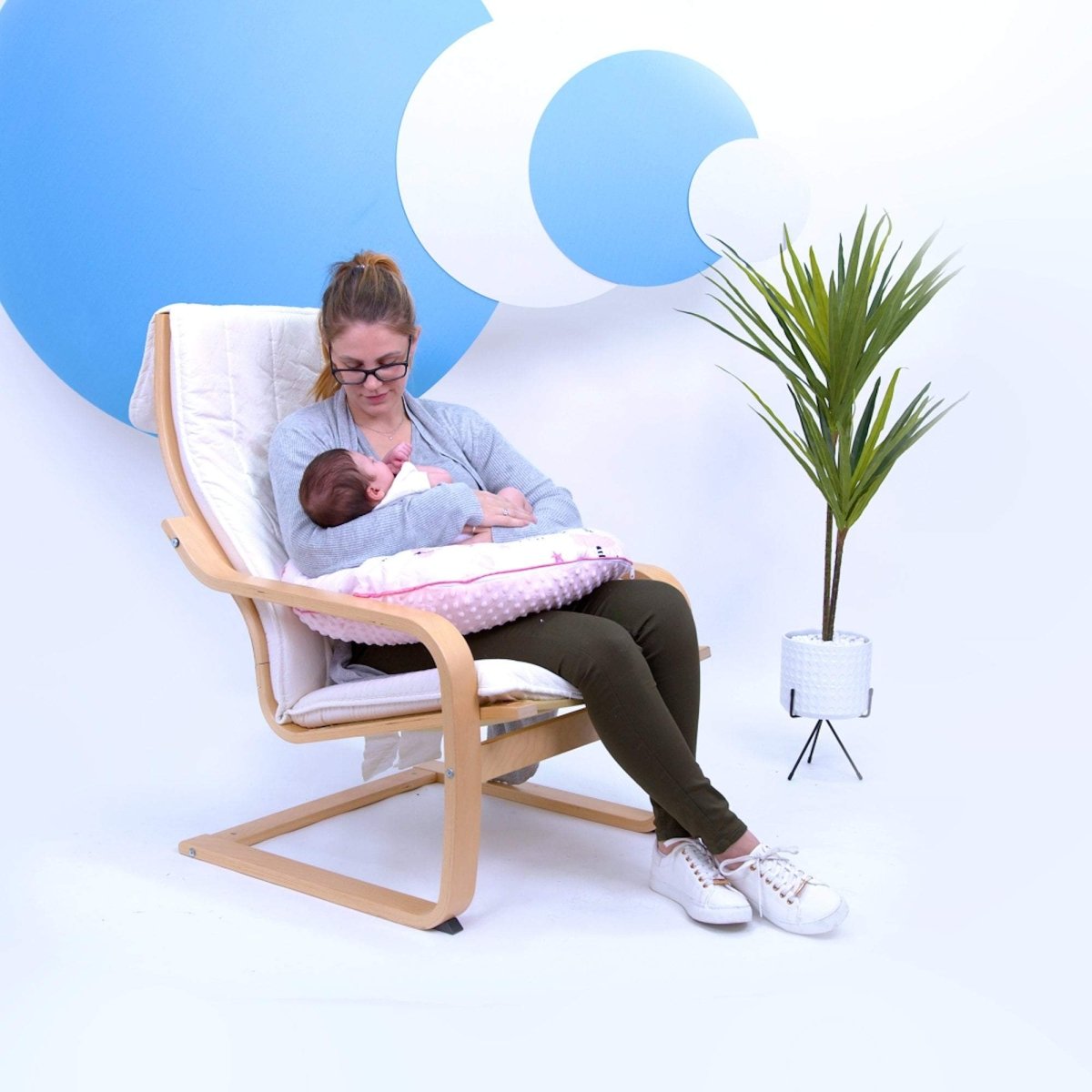 Woman breastfeeding a baby in a modern chair with a minimalistic background