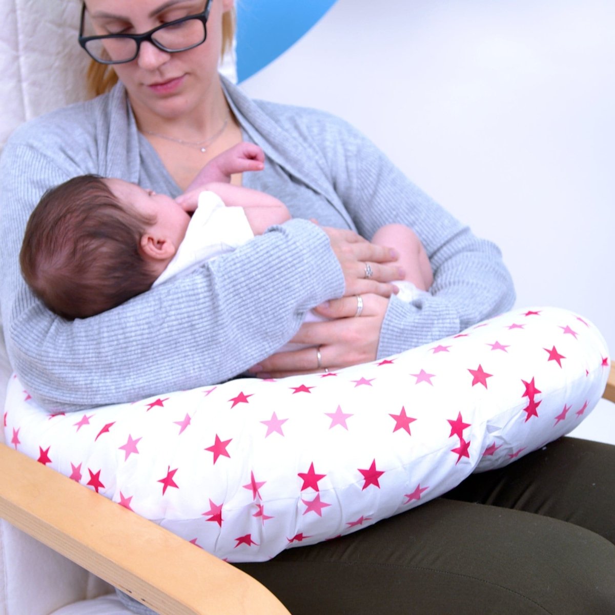 Woman breastfeeding a baby using a star-patterned pillow.