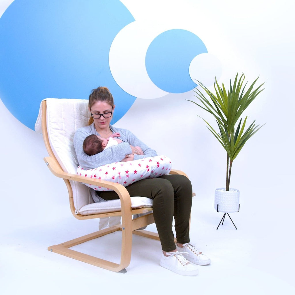 Woman breastfeeding a baby in a modern chair with a minimalistic background