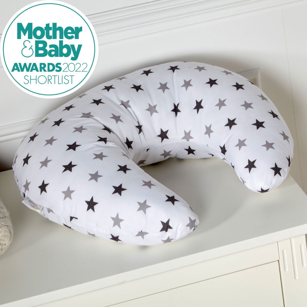 Breastfeeding pillow with star pattern on a white surface, featuring the Mother & Baby Awards 2022 Shortlist logo.