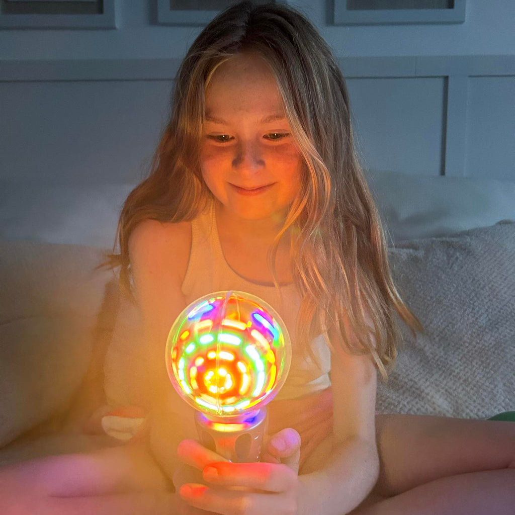 Child holding a colorful light-up toy in a cozy indoor setting