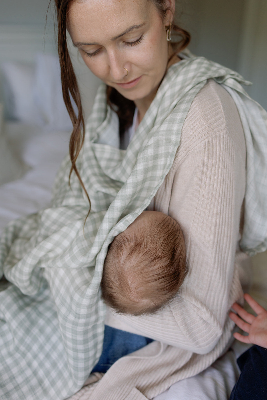 Woman holding a baby in a sling with a soft, indoor background