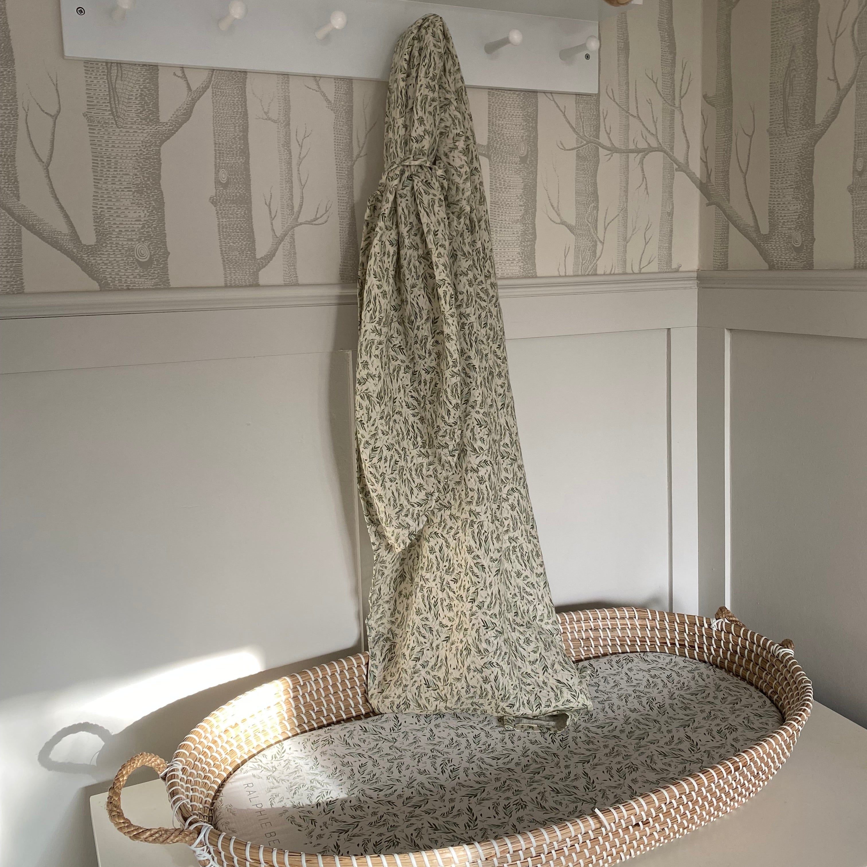 Nursery with a white shelf, woven basket, and patterned wall.