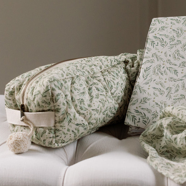 Green patterned bag and blanket on a white surface with a neutral background
