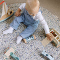 Baby playing with wooden toys on a speckled play mat