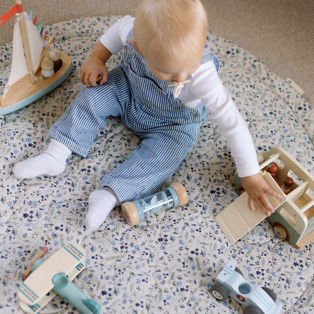 Baby playing with wooden toys on a speckled play mat
