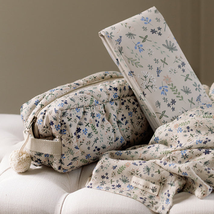 Floral-patterned pillows and blanket on a sofa against a neutral background