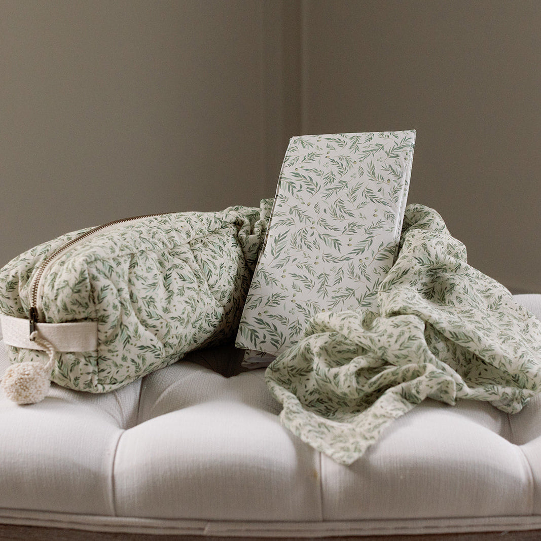 Green textured pillows and blanket on a white sofa against a plain wall