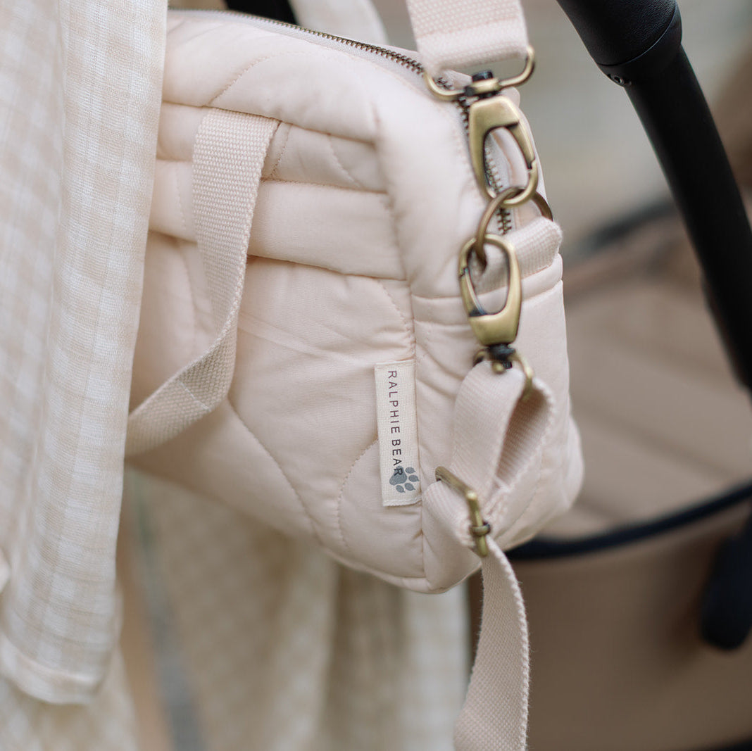 Close-up of a beige quilted handbag with a visible brand label, blurred background